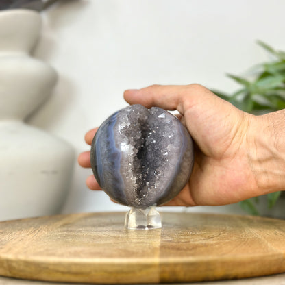 Eine Hand präsentiert die perfekt geschliffene Achat-Kristallsphäre, um die echten Dimensionen und den Durchmesser von 8,9 cm zu zeigen.
