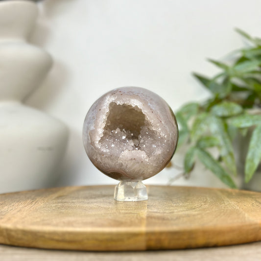 Echte Bänderachat-Sphäre aus Uruguay mit einem tief geöffneten, stark strukturierten Quarz-Druzy-Innenraum voller glitzernder Kristalle.
