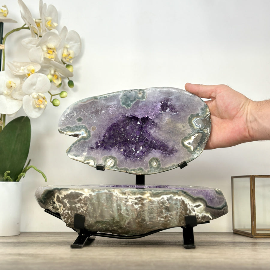 Eine Hand berührt die geöffnete Amethyst-Schatulle im Ständer, um die realen Proportionen und die Breite von 29 cm zu demonstrieren.