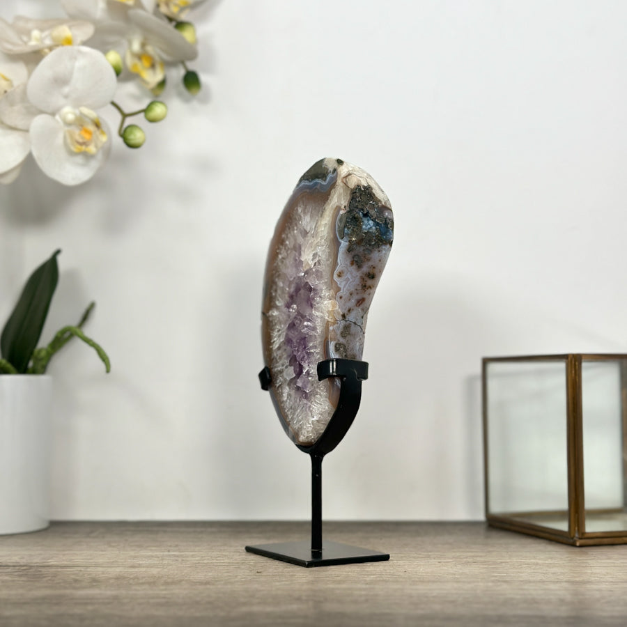 Detailansicht der unteren Kante der Kristallplatte, die das präzise Einsetzen des hellen Natursteins in die passgenaue, schwarze Metallhalterung zeigt.

