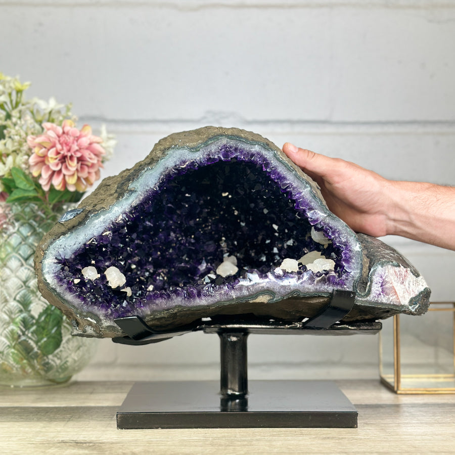 Eine Hand greift an den Rand der großen Amethyst-Geode, um die realen, massiven Dimensionen und die Breite von 41 cm zu demonstrieren.