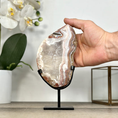 Eine Hand hält das Jaspis-Quarz-Portal im Design-Ständer, um die realen Proportionen und die Gesamthöhe von 20 cm zu demonstrieren.
