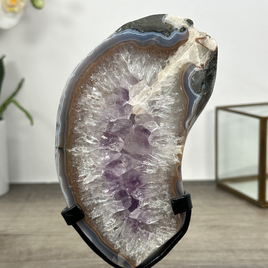 Makroaufnahme der funkelnden, hellen Quarz-Kristalle und der zartvioletten Amethyst-Segmente im Inneren der geschliffenen Natursteinplatte.
