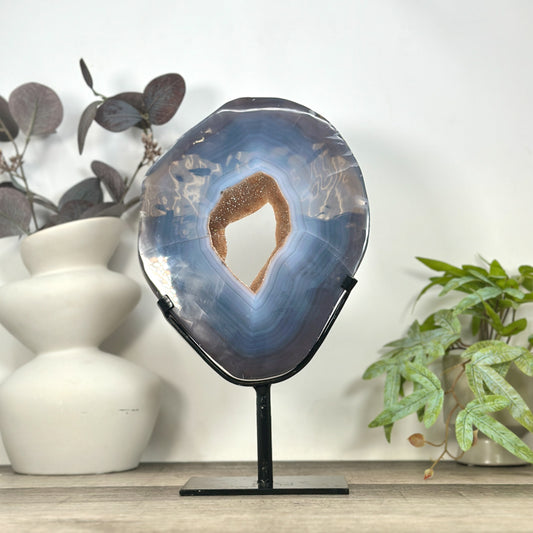 Großes ovales Kristall-Portal aus blauem Bänderachat und hellem Quarz aus Uruguay mit intensiv funkelnder Druzy-Oberfläche auf einem schwarzen Metallständer.