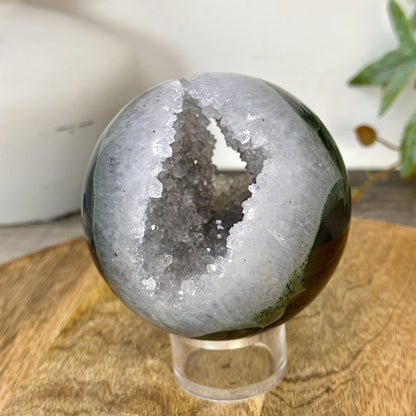 Schräge Seitenansicht der Naturstein-Sphäre, die die perfekte Symmetrie der Kugelform und die Tiefe der offenen Kristallhöhle abbildet.
