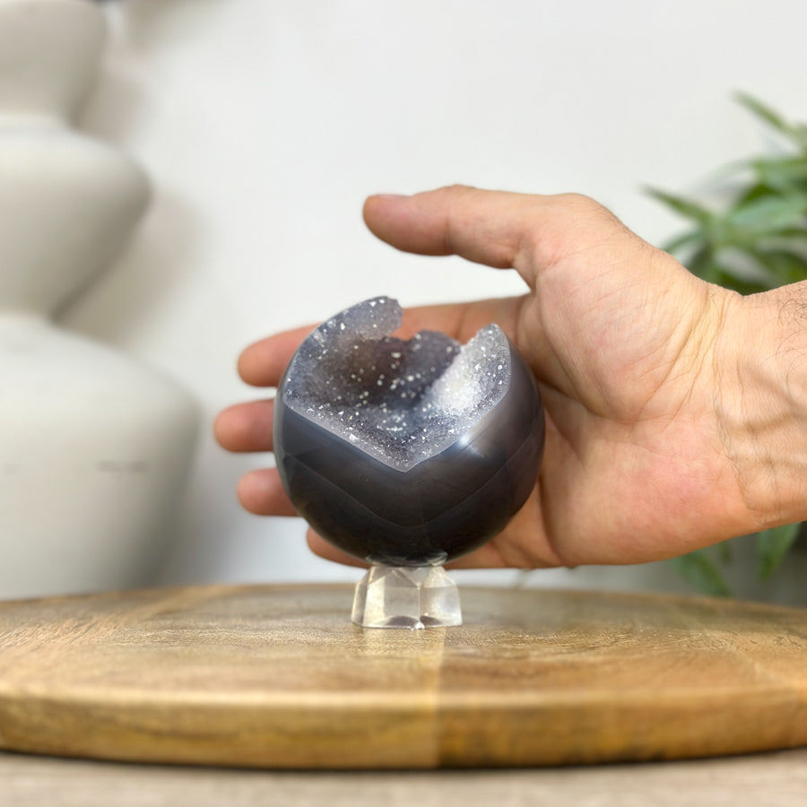 Eine Hand präsentiert die makellos geschliffene Zuckerquarz-Sphäre, um die echten Proportionen und den Durchmesser von 8 cm zu zeigen.
